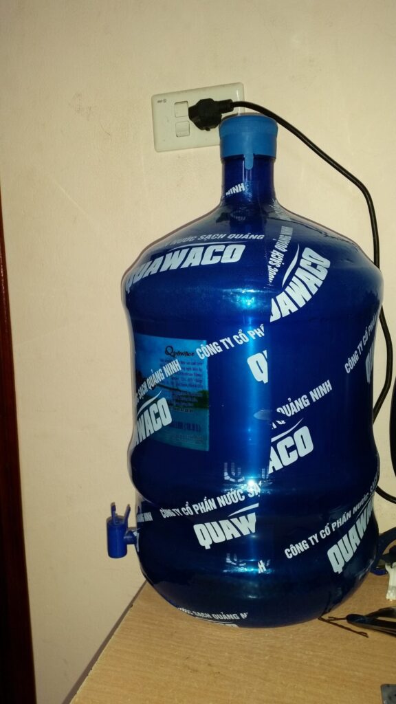 Large blue bottled water dispenser plugged into wall in Vietnam