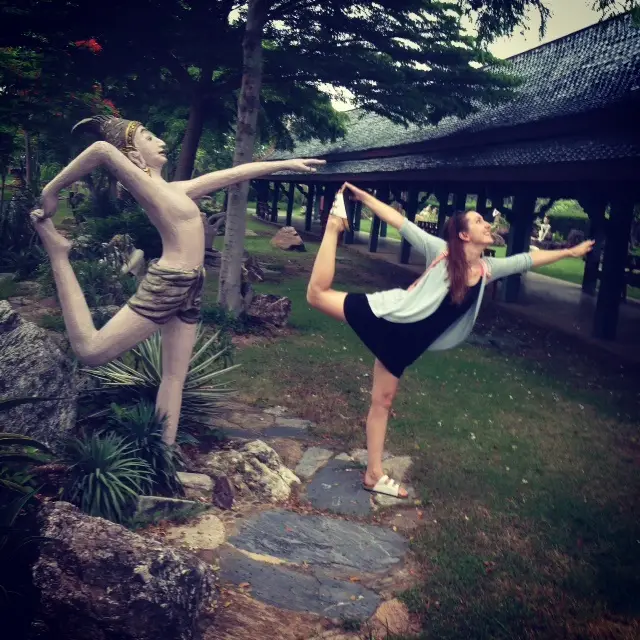 Woman posing in Thai park with statue during travel experience