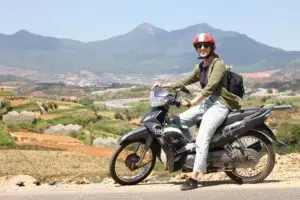 Woman riding motorbike in rural mountain landscape in Vietnam
