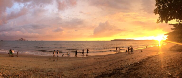 Beach sunset in Thailand with people relaxing by the sea