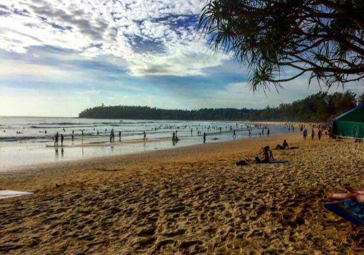 Beach scene in Phuket with people walking along the sandy shoreline