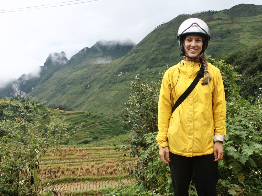 Teacher in yellow jacket standing in rural mountain landscape in Vietnam