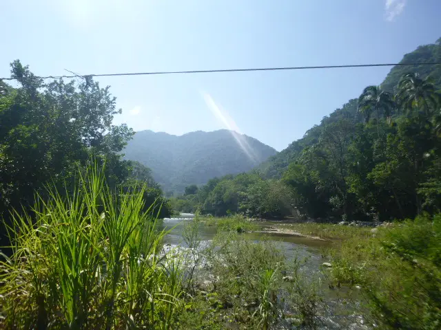 River running through tropical valley with mountains and dense greenery under bright sunlight in Mexico