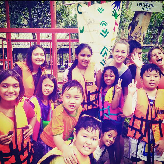Teacher with students wearing life jackets during activity in Thailand