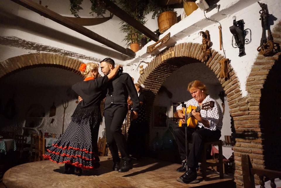 Flamenco dancers performing with guitarist in traditional Spanish setting