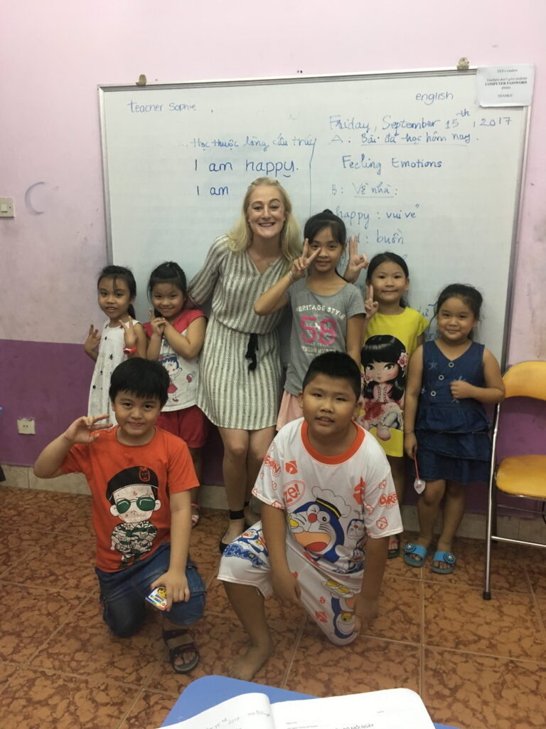 Teacher standing with young students in classroom in Vietnam