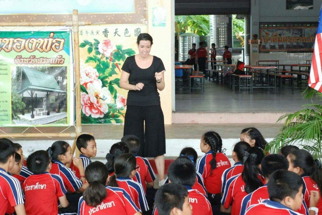 Teacher speaking to schoolchildren seated outdoors in Thailand