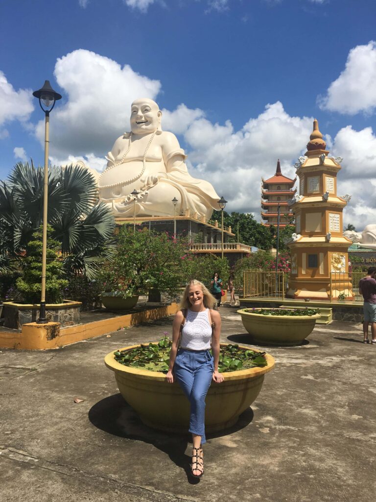 Teacher visiting temple with giant Buddha statue in Vietnam