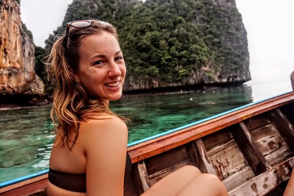 Woman sitting on boat in Thailand with limestone cliffs in background