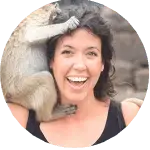 Smiling woman posing with a monkey on her shoulder in Thailand