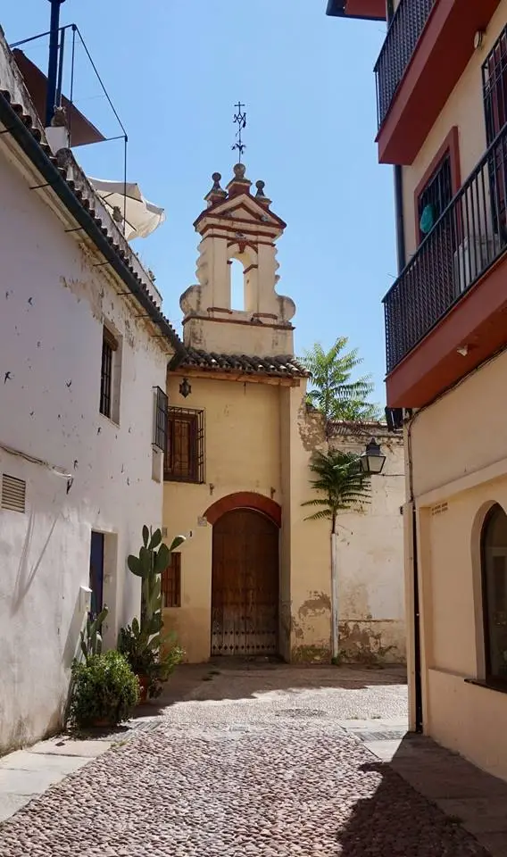 Narrow cobbled street in Cordoba with small chapel and white buildings