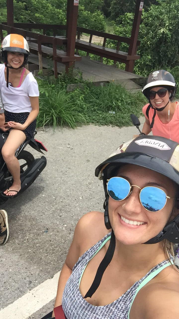 Two women riding scooters in Thailand