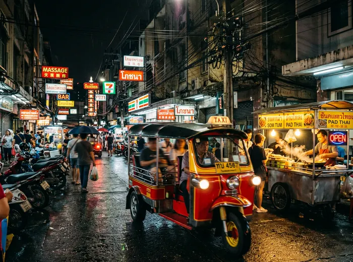 Bangkok tuk tuk in motion on a neon-lit alley at night